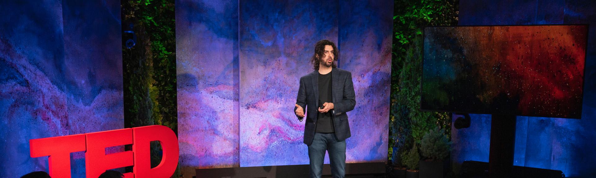 Azim Shariff giving a TED talk on the TED stage.